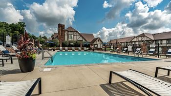 A pool area with a large swimming pool, lounge chairs, and a potted plant
